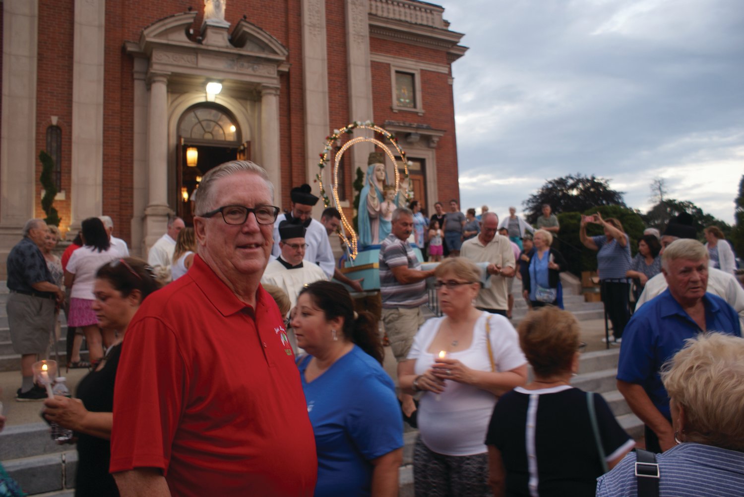GETTING READY: Mayor Ken Hopkins waits with the crowd outside St. Mary’s Church in Knightsville for the beginning of the candlelight procession held Friday evening. 